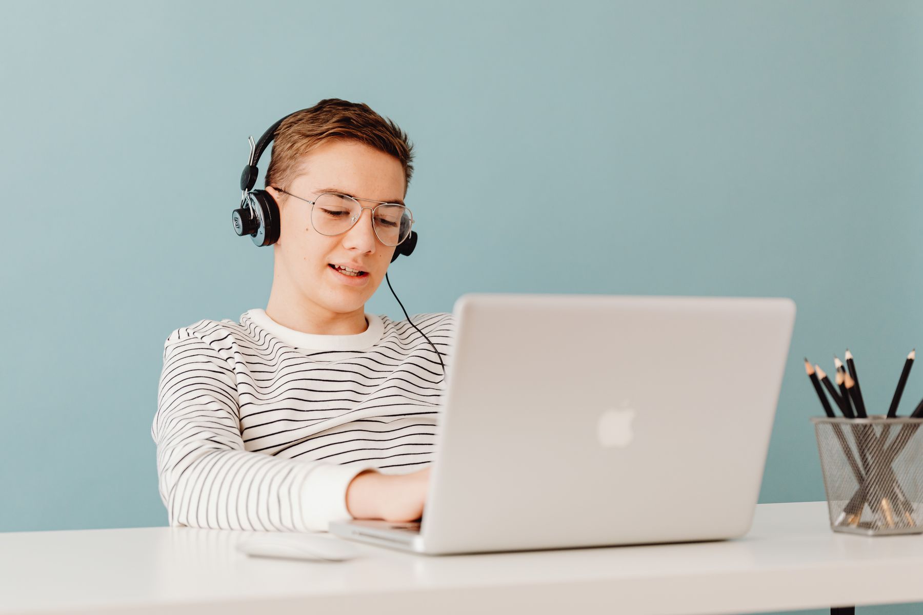 Chłopak w słuchawkach na lekcji online przy laptopie